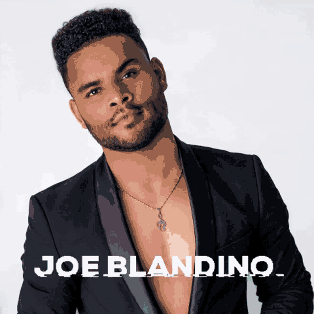 a man in a black suit and a necklace with the name joe blandino on the bottom