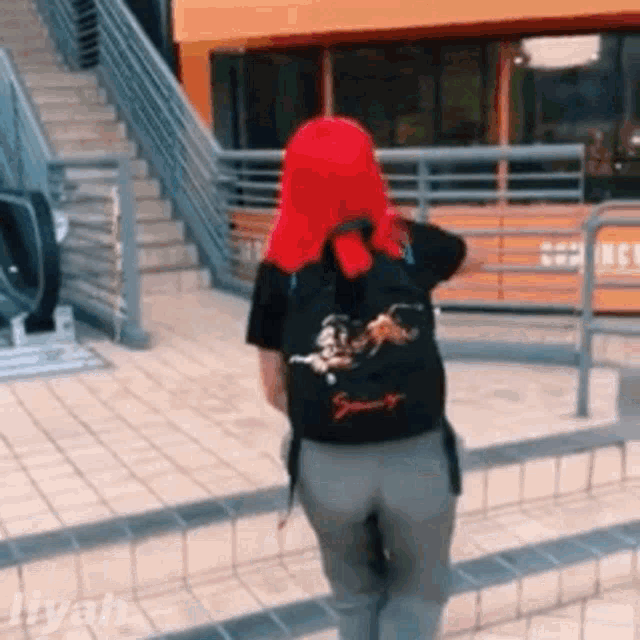 a woman with red hair and a backpack is walking down the street .