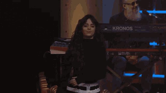a woman is dancing in front of a keyboard that says korg