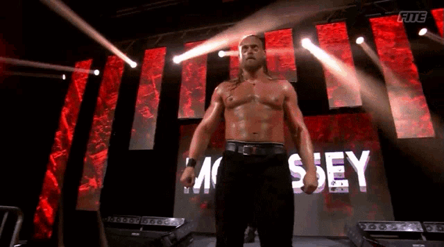 a wrestler is standing in front of a large screen that says mc sey on it