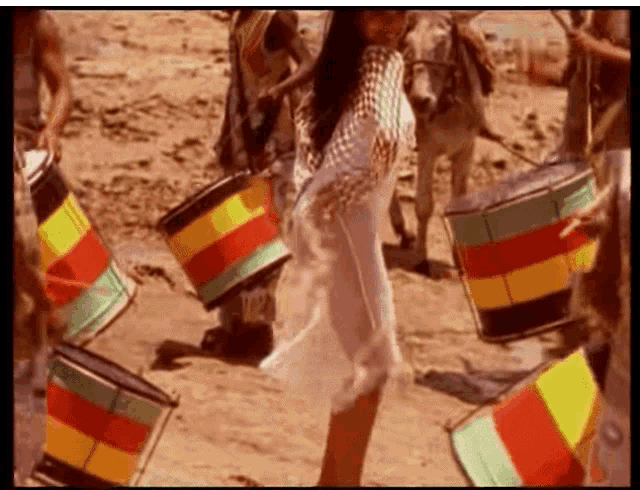 a woman in a white dress is dancing in front of a group of people playing drums