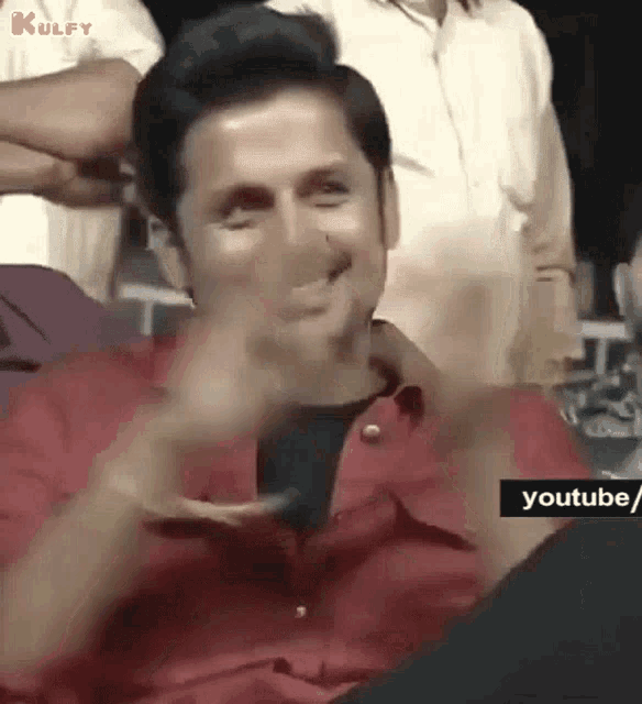 a man in a red shirt is making a funny face with his hand