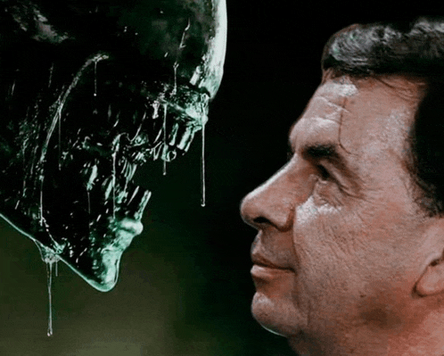 a man is looking at a green monster with liquid dripping from it 's mouth