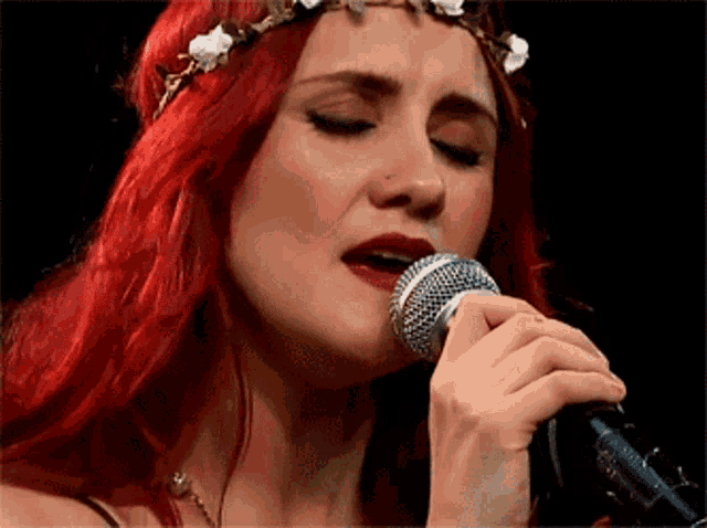 a woman singing into a microphone with a flower crown on her head