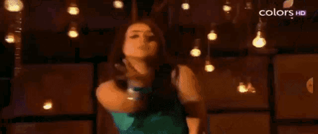 a woman in a green dress is blowing a kiss while standing in a room .