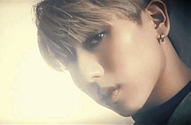 a close up of a young man 's face with a cross piercing in his ear