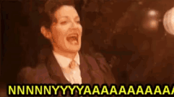 a woman in a suit and tie is screaming with her mouth wide open .