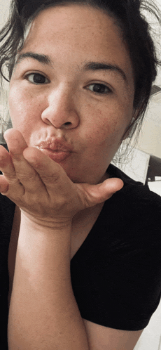 a young woman blowing a kiss with her hand