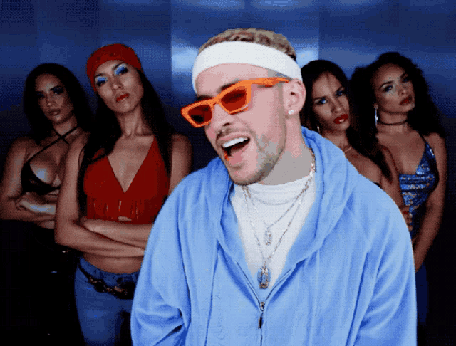 a man wearing sunglasses and a headband is standing in front of a group of women