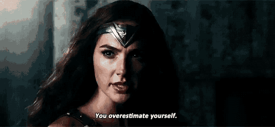 wonder woman is talking to herself in a dark room .