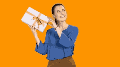 a woman in a blue shirt is holding a gift box with an orange ribbon .