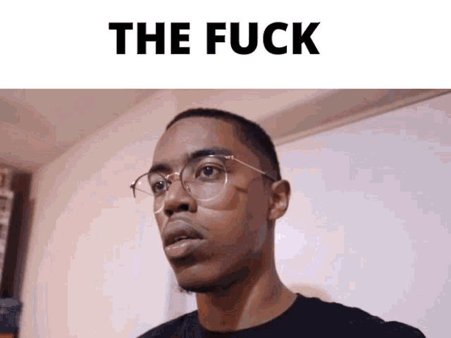 a man wearing glasses is standing in front of a white board that says " the fuck "