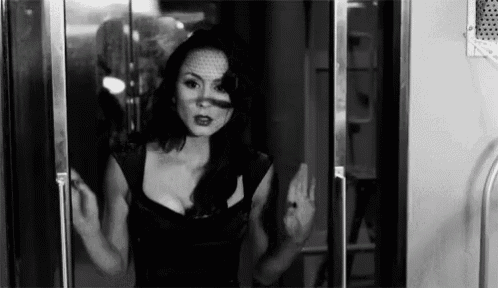 a woman in a black dress is standing in a doorway .