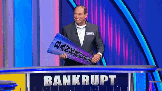 a man is holding a sign that says bankrupt on it