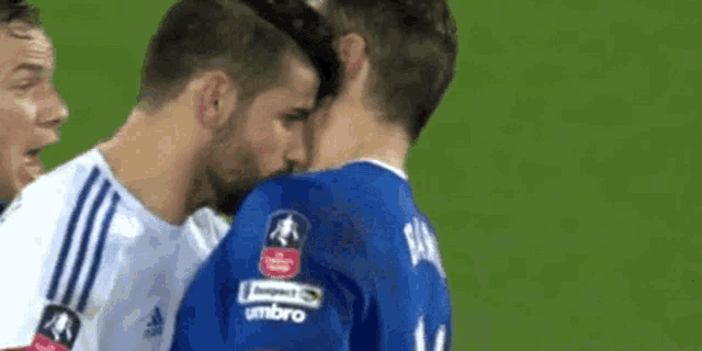 two soccer players are kissing each other on the field during a game .