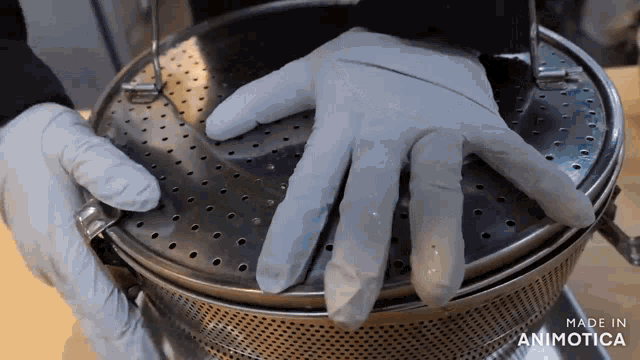 a person wearing gloves is putting their hand on top of a metal container