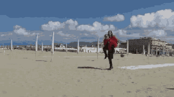 a man is carrying a woman on his shoulders at the beach
