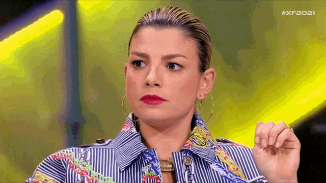 a woman wearing a striped shirt and hoop earrings is standing in front of a yellow light ..