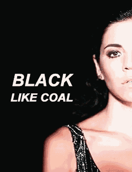 a woman in a black dress is standing in front of a black background with the words `` black like coal '' written above her .