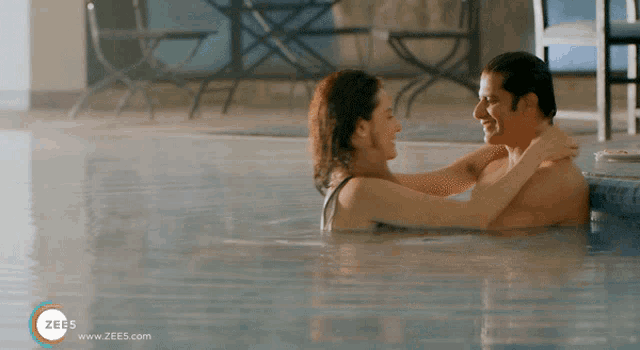 a man and a woman are in a swimming pool and the website zee5.com is visible