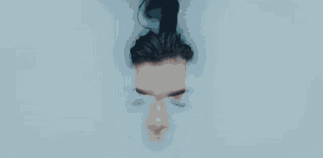 a woman is laying in a bathtub with her eyes closed and tears coming out of her eyes .