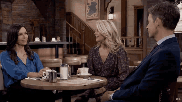 a man and two women sit at a table in a restaurant with dp written on the bottom right
