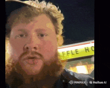 a man with a beard is standing in front of a sign that says waffle house