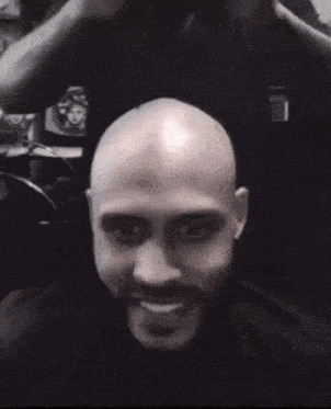 a man with a beard is getting his hair cut