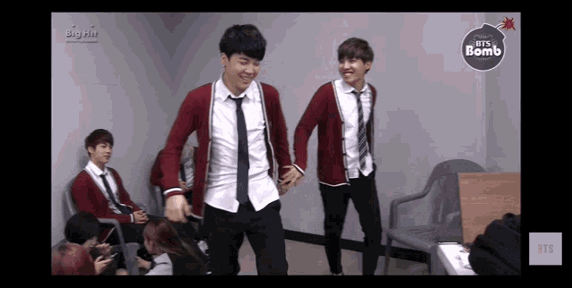 a group of young men are dancing in a room with a bts bomb logo