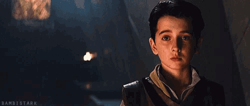 a young boy is looking at the camera in a dark room in a movie .