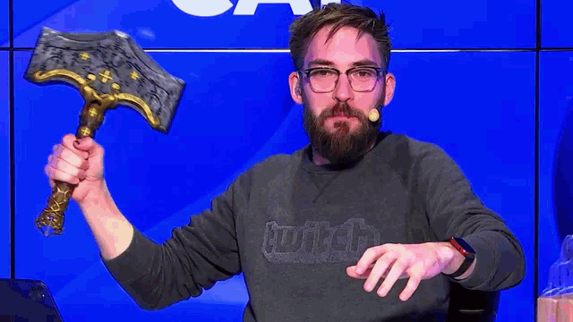 a man with a beard is holding a hammer and wearing a sweater that says hunter