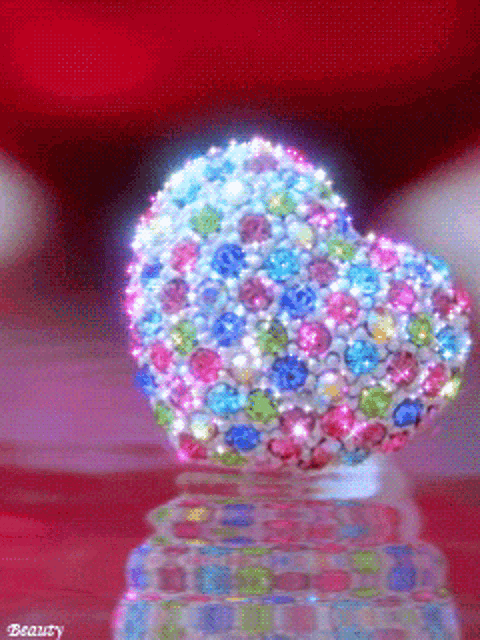 a heart shaped object is covered in rhinestones and has the word beauty on the bottom