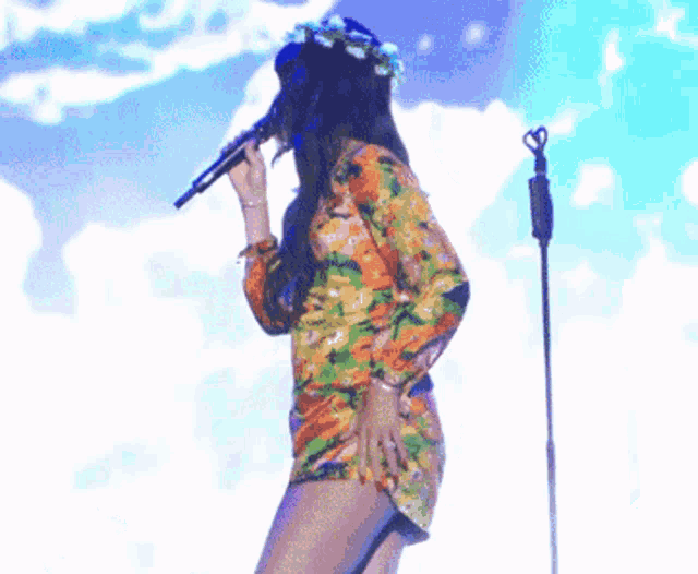 a woman singing into a microphone wearing a flower crown