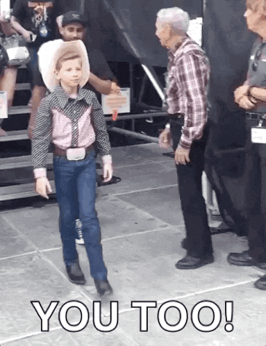 a young boy in a cowboy outfit is standing next to an older man with the words you too written on the ground