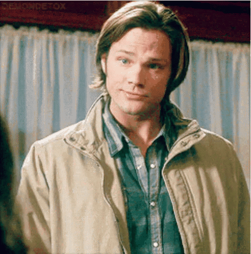a man wearing a plaid shirt and a tan jacket is standing in front of a window .