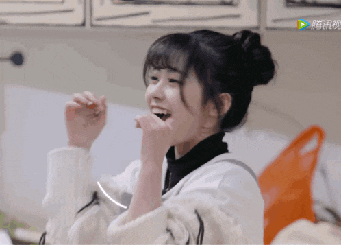 a girl with a bun on her head is smiling and eating