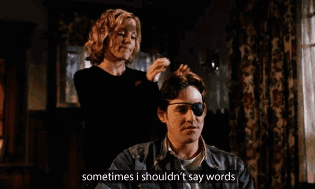 a man with a bandage on his eye is getting his hair done by a woman