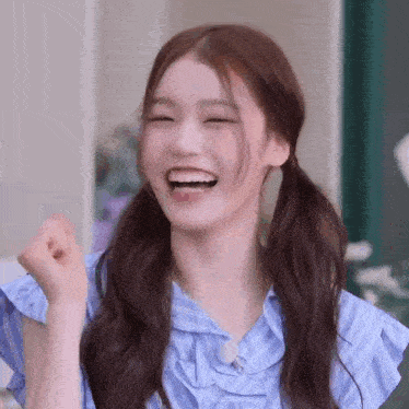 a close up of a girl with pigtails laughing and making a fist .