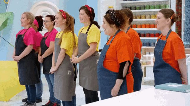 a group of women standing in a line wearing aprons with the letter c on them
