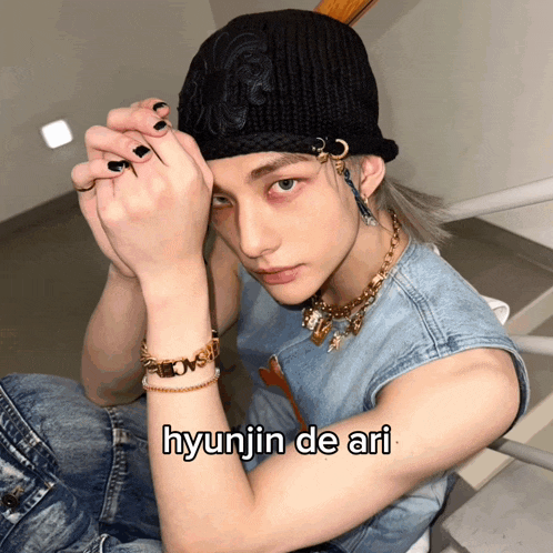 a young man wearing a hat and a necklace with the name hyunjin de ari