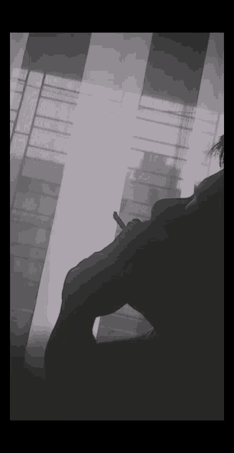 a silhouette of a person smoking a cigarette in front of a window