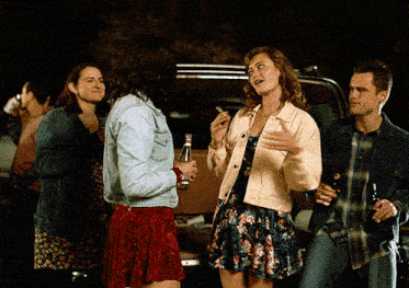 a group of people are standing around a car talking to each other