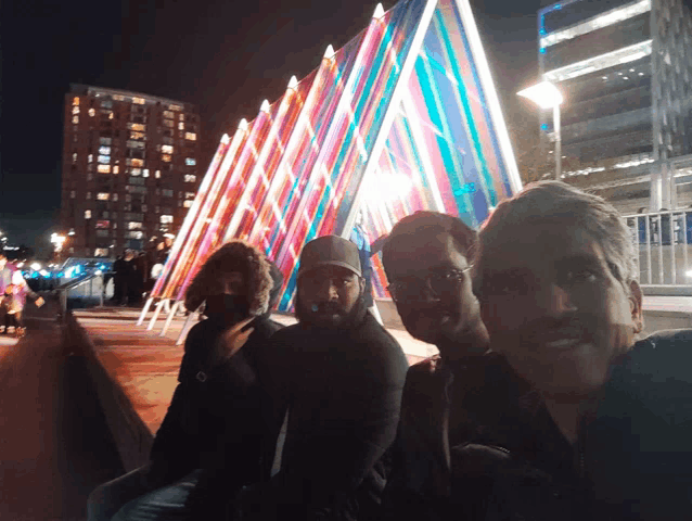 a group of people are posing for a picture in front of a colorful triangle