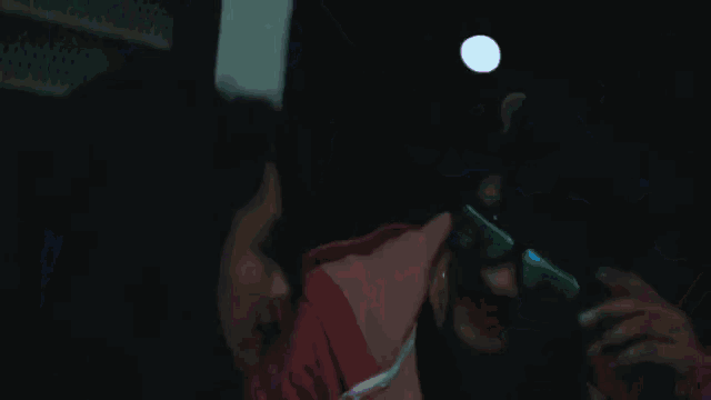 a woman wearing neon glasses is singing into a microphone in a dark room .