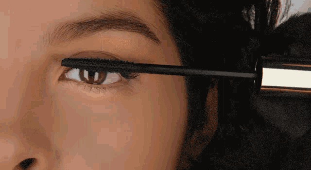 a close up of a woman applying mascara to her eyes