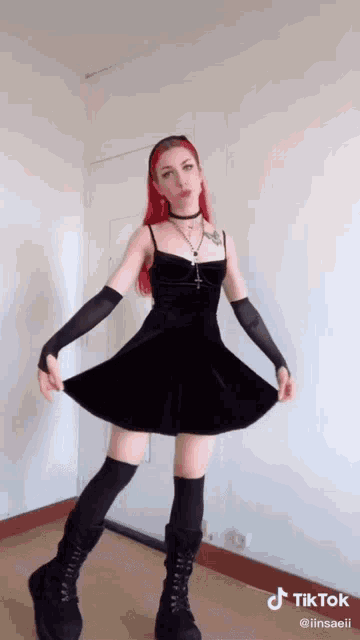 a woman with red hair is wearing a black dress and black boots .