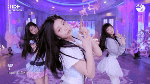 a group of girls are dancing in a room with purple walls and chairs hanging from the ceiling