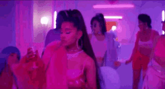 ariana grande is dancing in a pink room while holding a glass of wine .