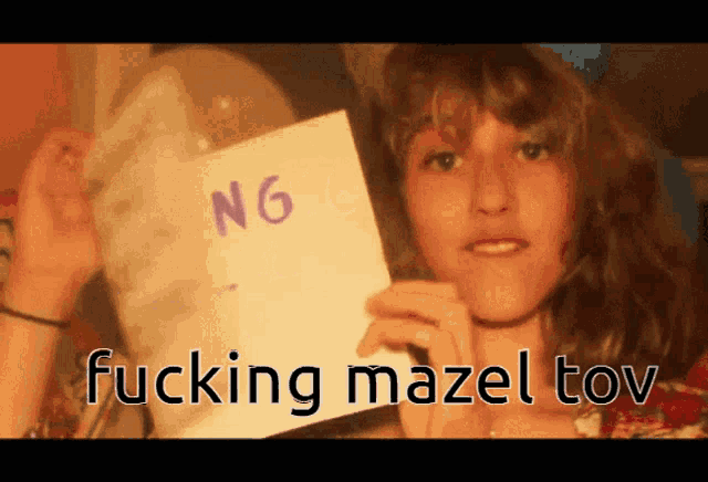a woman holds up a piece of paper that says ng fucking mazel tov