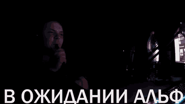 a man smoking a hookah in a dark room with the words " в ожидании альф " on the bottom right